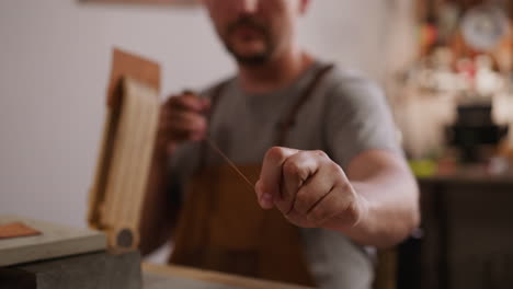 Master-unrolls-waxed-thread-for-leather-sewing-in-workshop