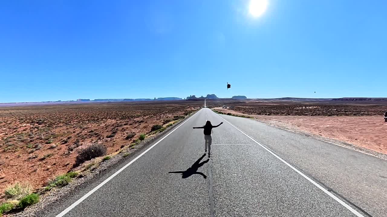 Donna che cammina su una lunga strada desertica verso montagne lontane