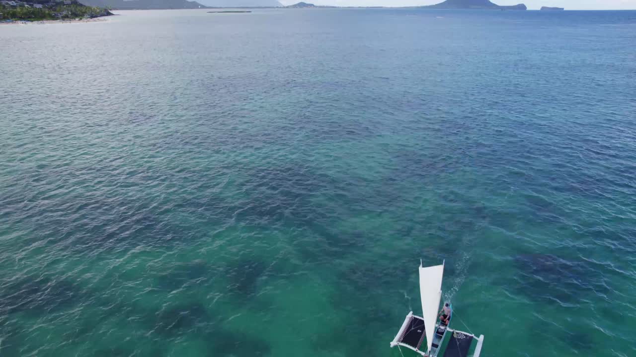imágenes de drones de una canoa de vela en el agua cristalina del océano