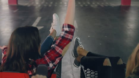 rear view of two cheerful caucasian girls having fun while they are ridding in trolleys in a empty parking