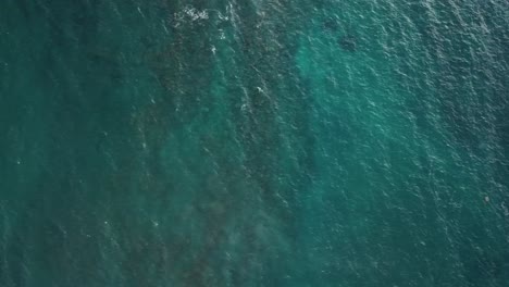 Drone panning left aboce ocean and underwater rocks in Kauai, Hawaii
