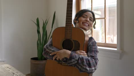 happy smiling puerto rican girl hugging acoustic guitar in joyful embrace