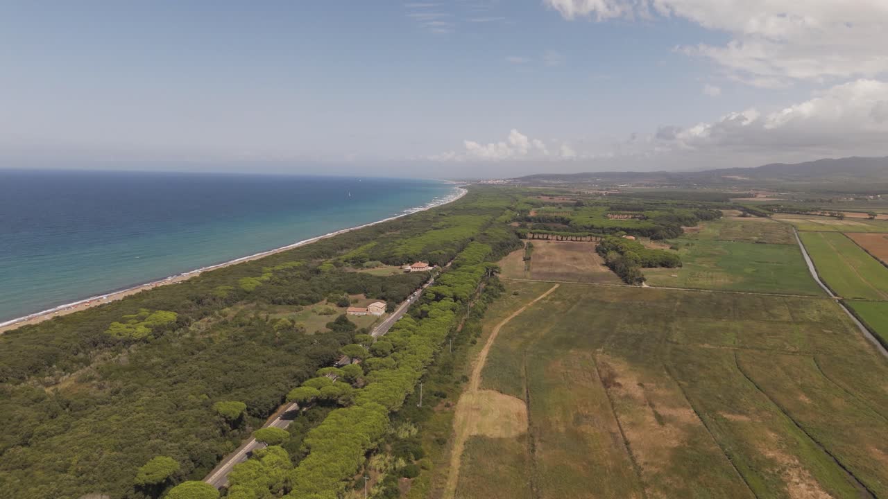 Ampia veduta aerea della costa toscana con terreni agricoli, aree boschive, dolci colline e acque blu profonde del Mediterraneo. Ottima per raccontare storie di viaggi, agricoltura, natura e ambiente.