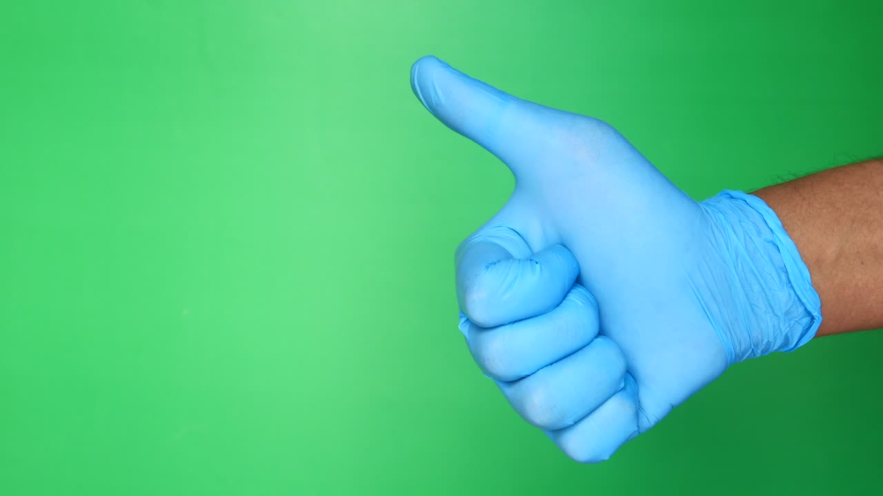 의료 장갑을 입은 사람의 손이 엄지손가락을 보여주는 클로즈업.