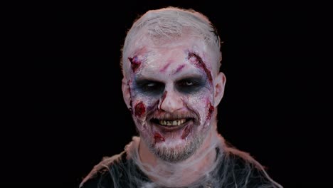 playful sinister man halloween crazy zombie with bloody wounded scars face blinking eye toothy smile