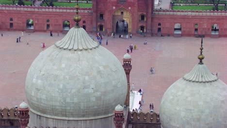 lahore, pakistán, minaretes de la mundialmente famosa mezquita badshahi vista aérea de cerca, visitantes damas, caballeros y niños están en la mezquita, fieles en el suelo de la mezquita, cometas negras