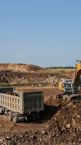 heavy equipment at construction site: excavator loading dump truck