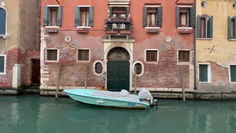 4k static shot of a serene venetian canal: a boat drifting at the entrance of a magnificent historical building in venice, italy, showcasing unique architecture and rich cultural heritage