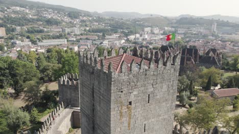 Aerial-orbit-watchtower-of-Guimaraes-Medieval-Castle,-City-buildings-background