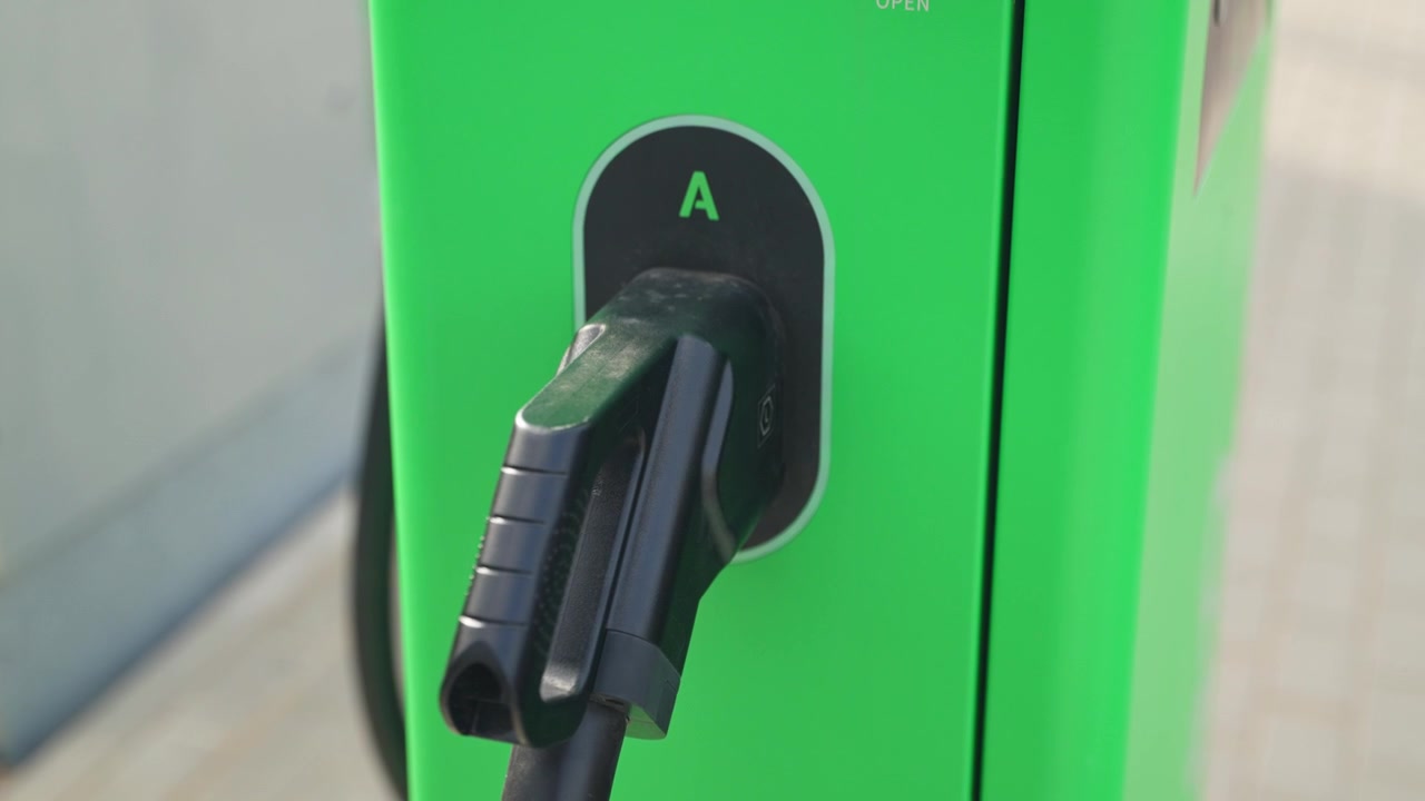 Connecteur de charge pour véhicule électrique monté sur une borne verte moderne.