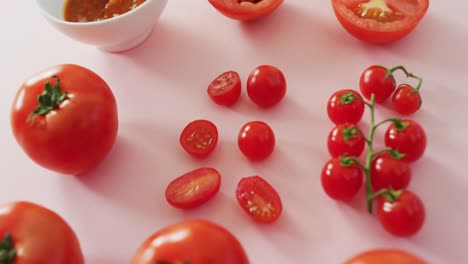 Video-of-fresh-red-tomatoes-and-tomato-sauce-with-copy-space-on-pink-background