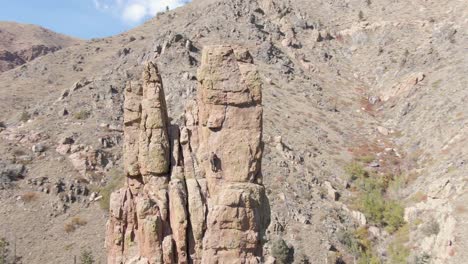 Orbiting-shot-of-a-rock-climber-making-their-way-up-a-skinny-and-unique-rock-pillar