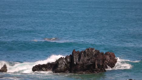 slow-motion video of waves hit black rocks