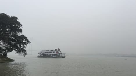 static shot of a passenger ferry sailing on hooghly river with background barely seen in kolkata, india