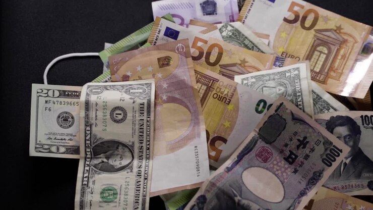 Un masque facial gît sous des dollars, euros, yens et livres sterling qui défilent à l'envers. Coronavirus, COVID 19. Crise financière. Effondrement. Chômage. Récession, crise, krach boursier