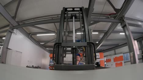 a worker in a warehouse uses a hand pallet stacker to transport pallets.