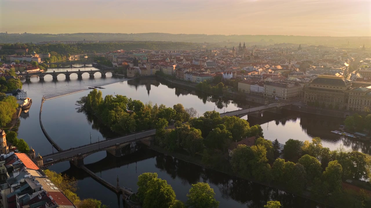 Vista aerea ad alta quota del fiume Moldava con numerosi ponti, isole boscose e il centro storico di Praga che risplende nella luce nebbiosa del mattino, Praga, Repubblica Ceca