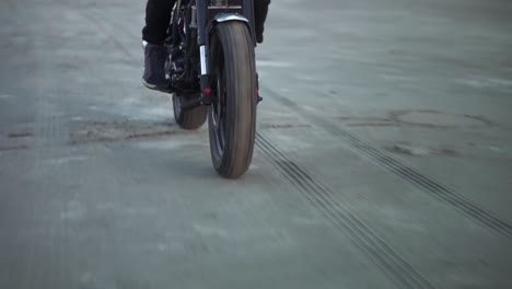 motociclista montado en una bicicleta deportiva negra con casco y faros delanteros encendidos. frente al mar, puesta de sol