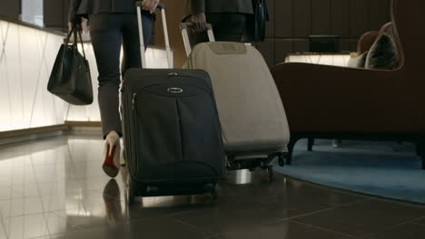 businessman and businesswoman enter the hotel with suitcases and talk to the receptionist