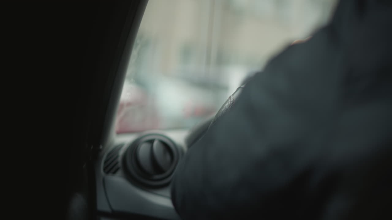 Dutch angle shot of car lover behind wheel with hands positioned for control, interior view tilted to emphasize motion and tension in urban commute setting with blurred cityscape through side window