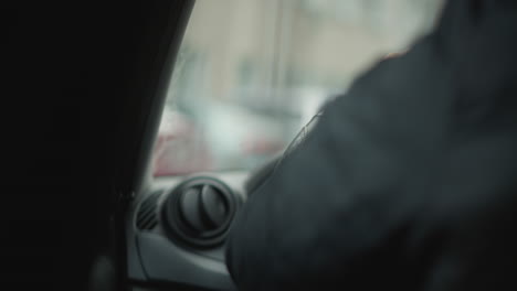 dutch angle shot of car lover behind wheel with hands positioned for control, interior view tilted to emphasize motion and tension in urban commute setting with blurred cityscape through side window