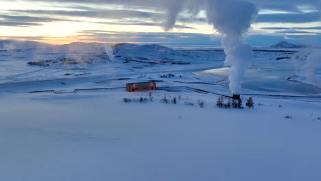 white smoke comes from the geothermal installations in a white snowy landscape in iceland after sunset