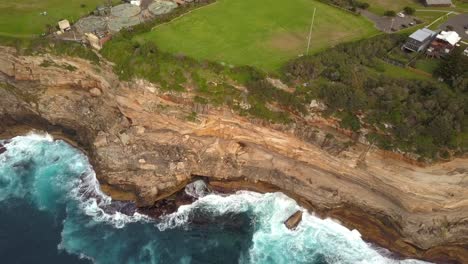 Epische-Drohnenaufnahme-Von-Meereswellen,-Die-Gegen-Klippen-Und-Felsen-Schlagen,-In-Der-Nähe-Eines-Parks,-Sydney,-Australien