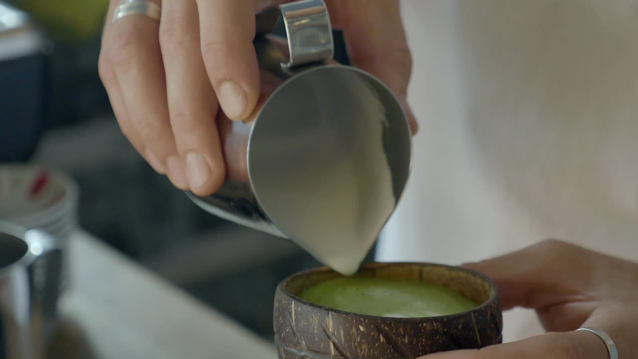 barista vertiendo matcha latte en la cáscara de coco