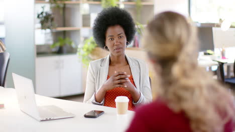 happy diverse female creative colleagues in discussion using laptop in office, slow motion