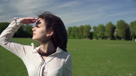 retrato de una modelo italiana hermosa y de moda caminando en un parque tranquilo, mirando a su alrededor, usando una camisa transparente en londres, reino unido