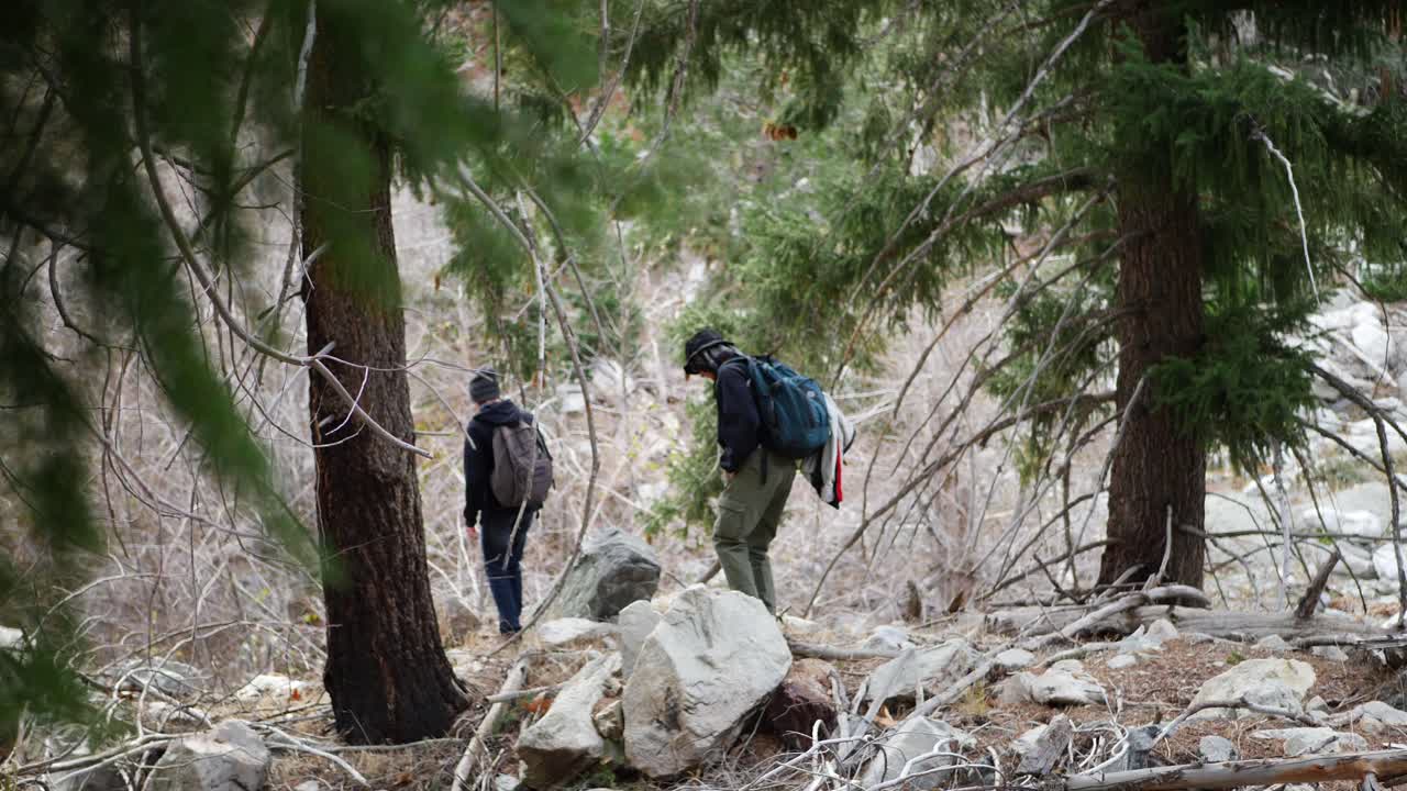 A father and son walking in nature down a rugged hiking trail through the mountains and forests of California