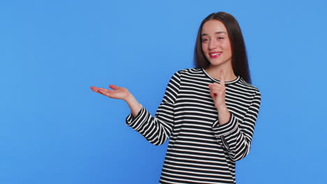 mujer joven mostrando los pulgares hacia arriba y señalando a la izquierda en el espacio en blanco lugar para su logotipo de publicidad