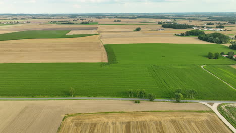 aerial view of a diverse agricultural landscape with green and brown fields, showcasing the variety of crops and farming methods used in modern agriculture