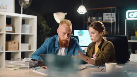 Closup young business couple discussing project results in night office