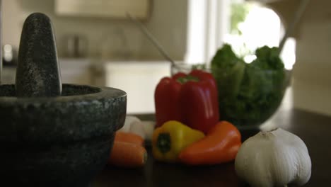 Mortar,pestle-and-vegetables-on-kitchen-worktop