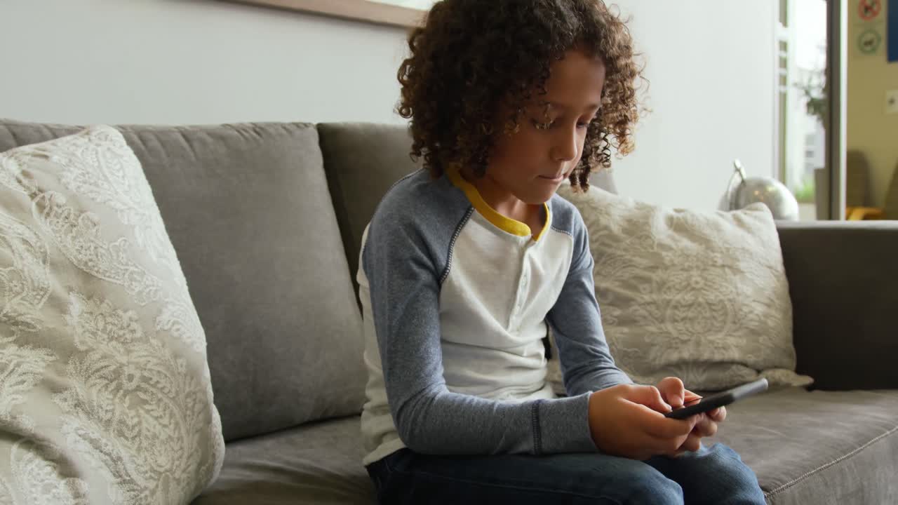 Front view of Caucasian boy playing game on mobile phone in lobby at hospital 4k