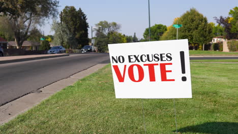 election voter rally sign next to road with cars driving by close up, no excuses vote