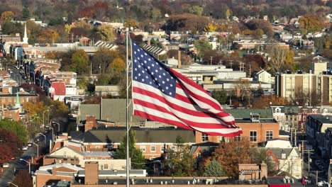 american flag waving over urban cityscape with autumn foliage