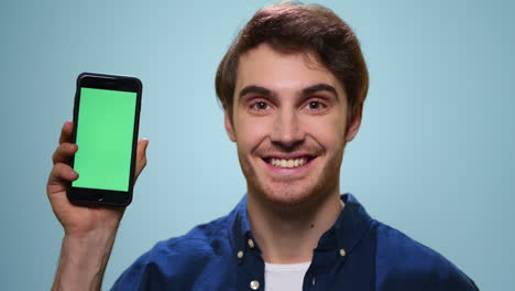 Hombre-Mostrando-Teléfono-Inteligente-Con-Pantalla-Verde-En-El-Estudio.-Estudiante-Mostrando-Teléfono-Móvil