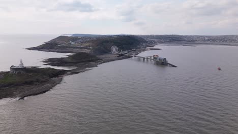 aerial panoramic approach to the big wheel at mumbles pier, showing details of the structure and movement under cloudy sky
