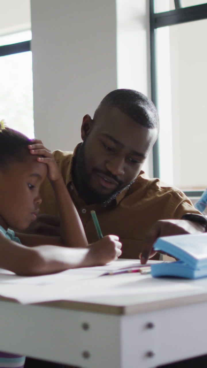 video de un feliz maestro afroamericano ayudando en las lecciones a una chica afroamericana