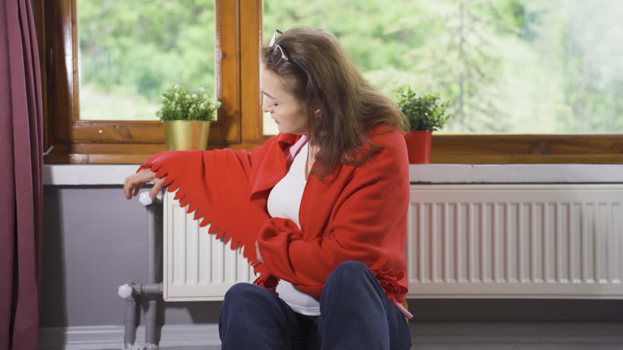 la mujer baja la temperatura del calentador y tiene frío.