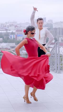 dancers in vibrant red dress and elegant attire performing a passionate dance on a rooftop