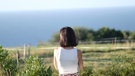 夏の間緑豊かな丘の斜面から海を見つめる女性