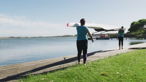 Two-senior-caucasian-women-carrying-a-rowing-boat