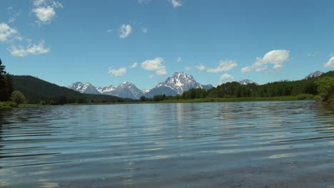 view from snake river of the tetons reflecting in the rippling water in summer in grand teton national park