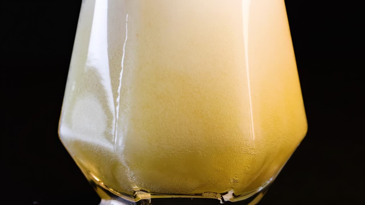 Primo piano di schiuma che trabocca da un bicchiere dalla forma unica, catturando il dinamico processo di fuoriuscita.