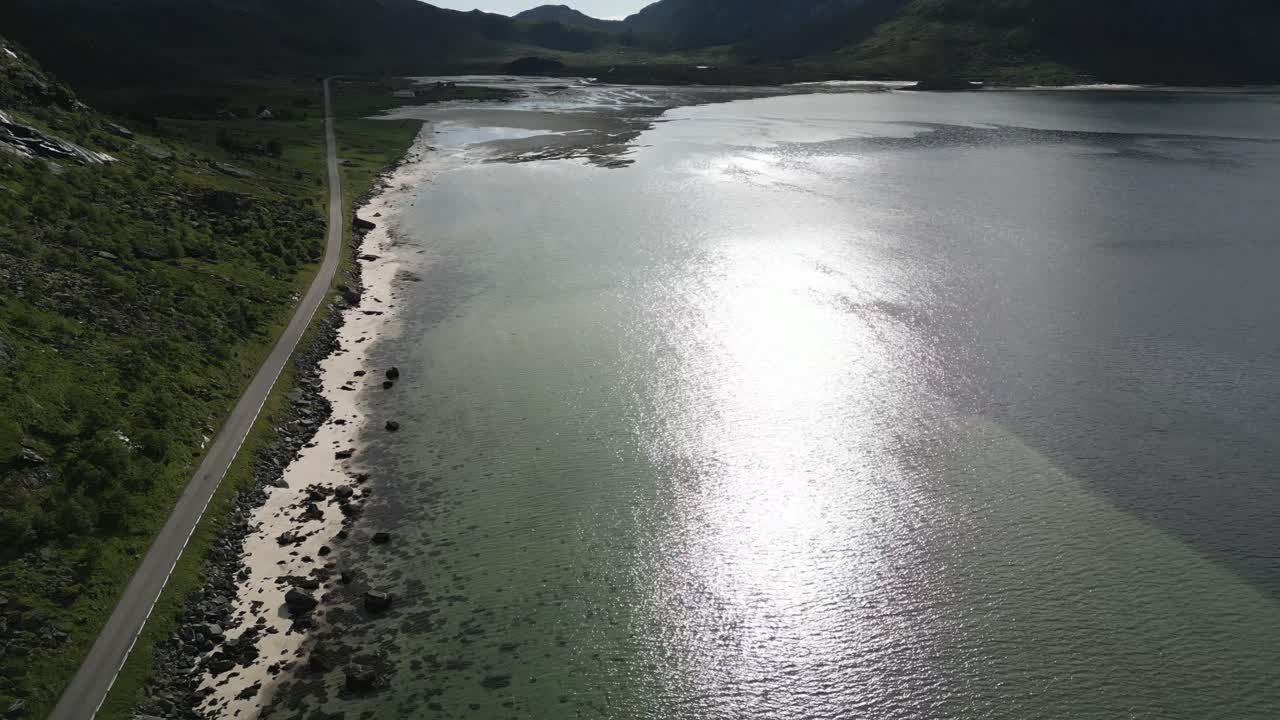 노르웨이 로포텐(lofoten)의 피요르드(fjord)를 보여주는 공중 전망, 모든 방향으로 산을 따라 달리는 도로와 맑은 물을 보여주는 하향 운동