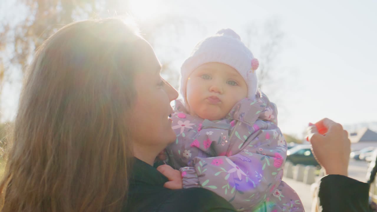 A joyful moment between mother and daughter in sunlight, capturing their warm connection and playful interaction amidst nature's beautiful backdrop