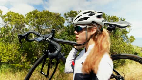 female cyclist carrying bicycle on countryside road 4k